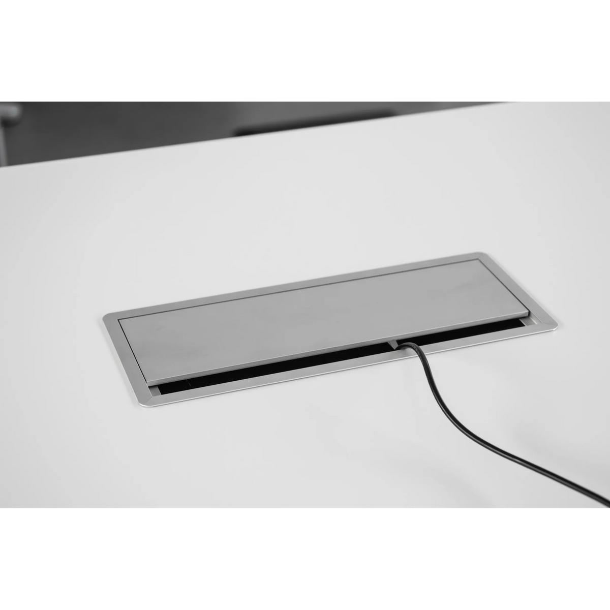 Silberne Kabelklappe des Zubehörs ELKL 30 mit herausgeführtem Kabel auf einer weißen Tischplatte von hjh OFFICE PRO