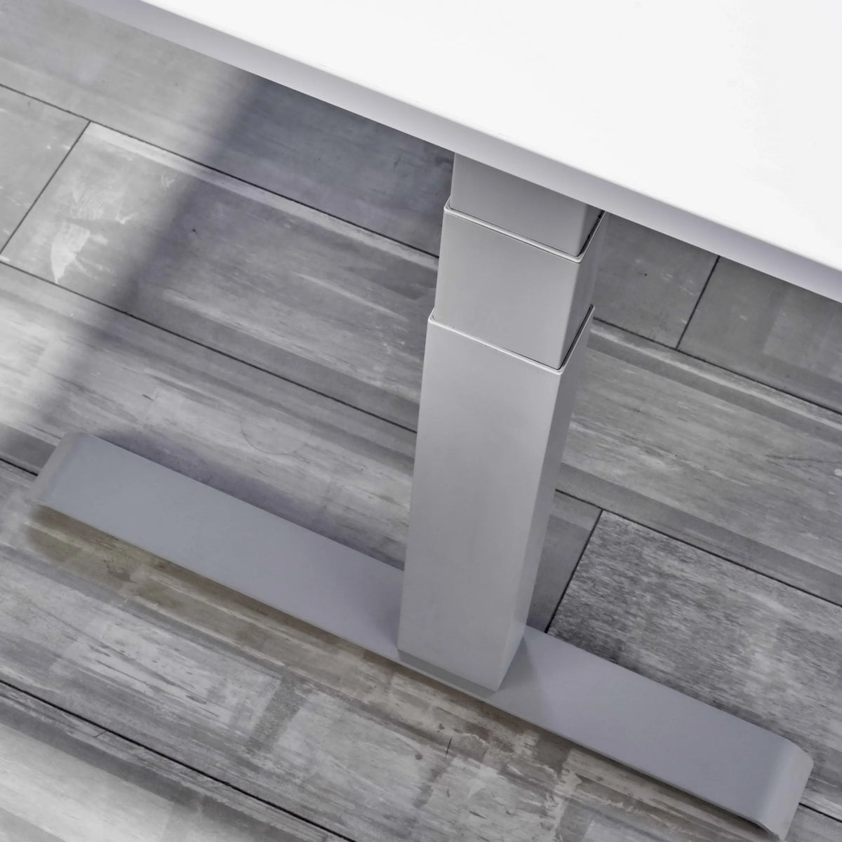 Höhenverstellbares Gestell des elektrischen Schreibtischs XDKB 19 G mit T-Fuß auf grauem Boden von hjh OFFICE PRO